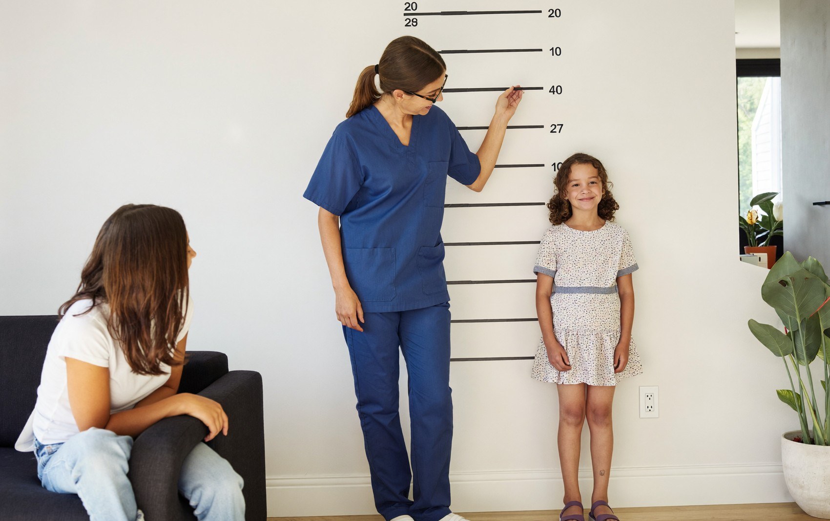 Une infirmière mesure la taille d’une fillette contre le mur