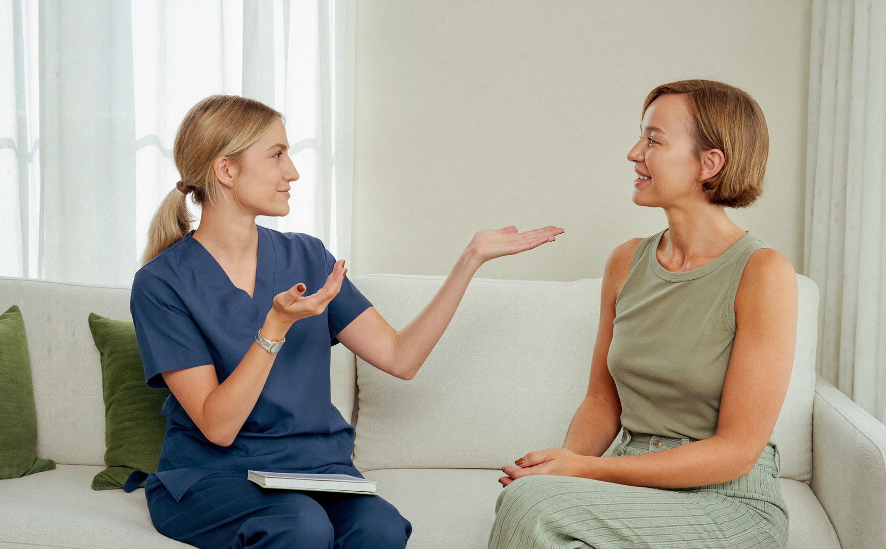Une infirmière conseille une femme assise à ses côtés sur le canapé